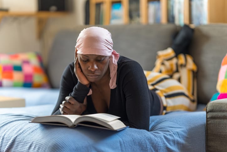 Photo shows a woman reading a book on her couch/Getty Images