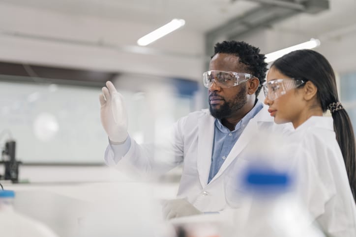 Photo shows two scientists analyzing a sample in a lab/Getty Images
