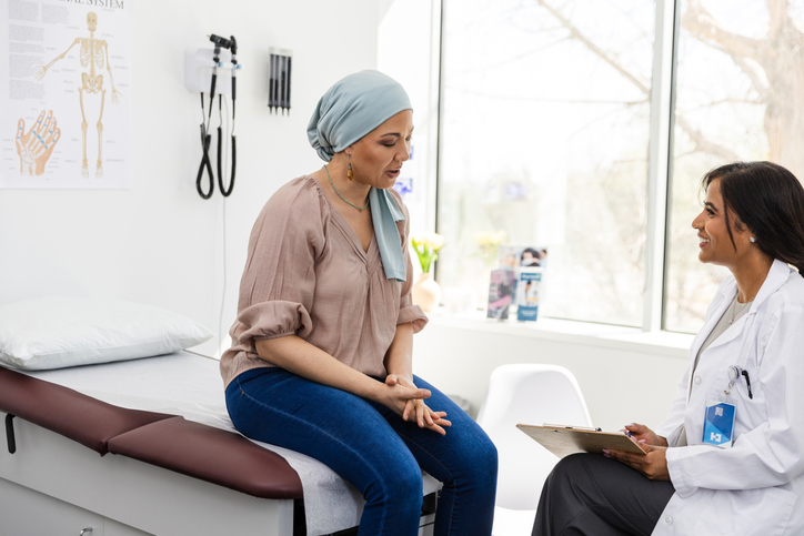 Photo shows a patient with breast cancer talking to her doctor in a medical office/Getty Images
