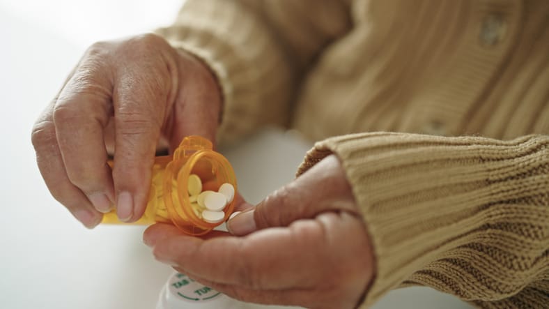 Photo shows a senior person pouring pills into their hand/Getty Images