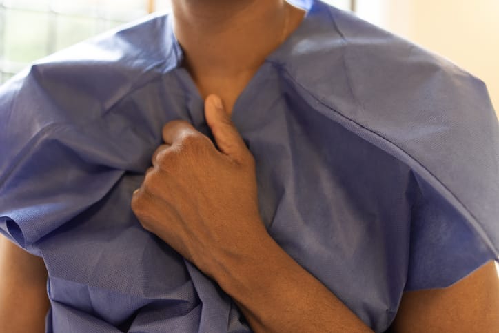 Photo shows a woman clutching her paper gown in a hospital/Getty Images