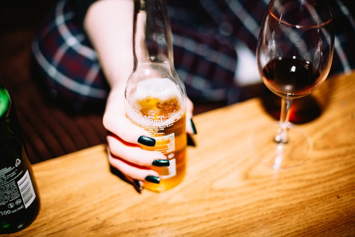 Photo shows a young woman holding a bottle of beer/Getty Images