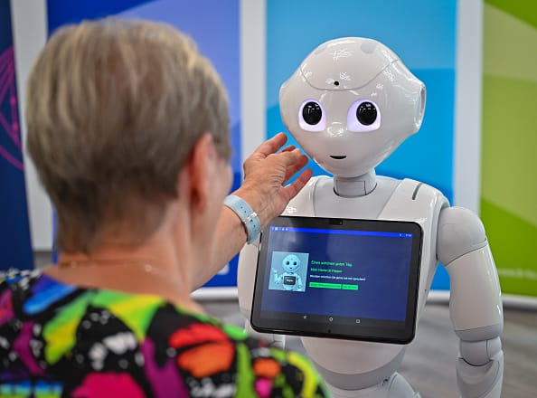 Photo shows a live interaction between a simulated patient and a robot can be seen at a press event at the Carl-Thiem-Klinikum Cottbus. A pilot study is currently being conducted at the Brandenburg University of Technology Cottbus-Senftenberg (BTU) to investigate the effects of the interaction modalities of a social robot (Pepper) on the engagement and perception of test subjects in typical care situations. Photo: Patrick Pleul/dpa (Photo by Patrick Pleul/picture alliance via Getty Images)