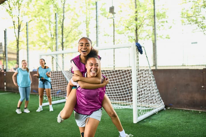 Photo shows two friends laughing while playing sports together/Getty Images