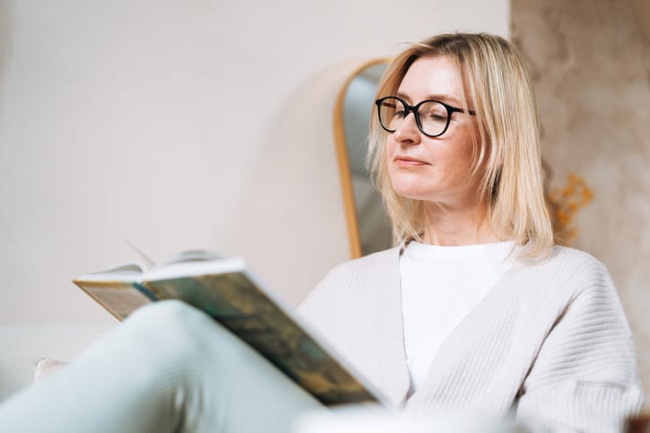 Photo shows a woman reading in bed/Getty Images