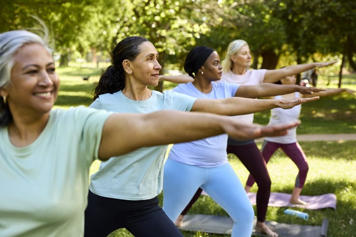 Photo shows a group of adult women in a pilates class outdoors/Getty Images