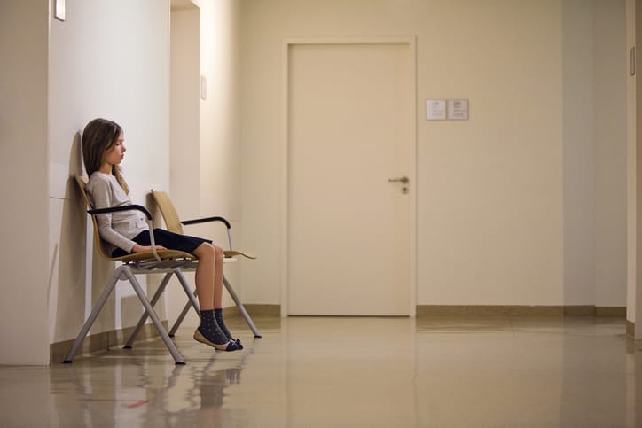 Photo shows a child sitting alone in a hospital waiting room/Getty Images