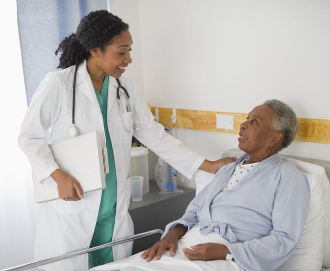 PHoto shows a doctor speaking to a patient in a hospital room/Getty Images