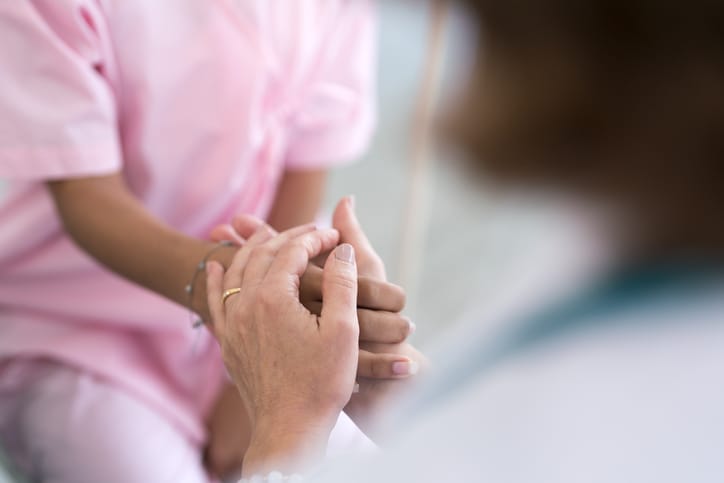 Photo shows a close up image of doctor holding a patient's hand/Getty Images