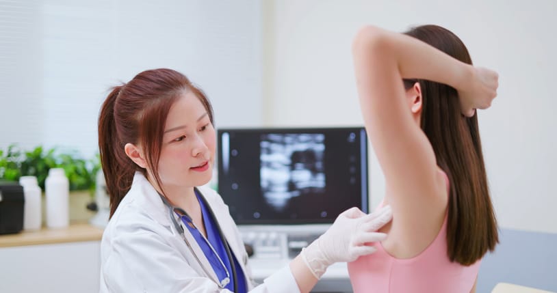 Photo shows a doctor examining a woman's lymph nodes in her armpit/Getty Images