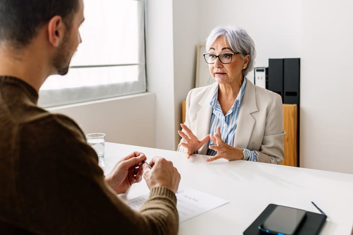 Photo shows a senior woman talking with a human resources representative/Getty Images