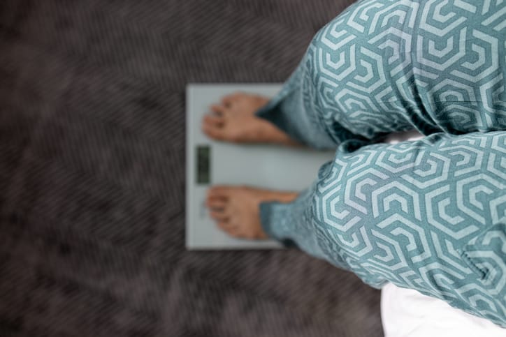 Photo shows a woman weighing herself on a digital scale/Getty Images