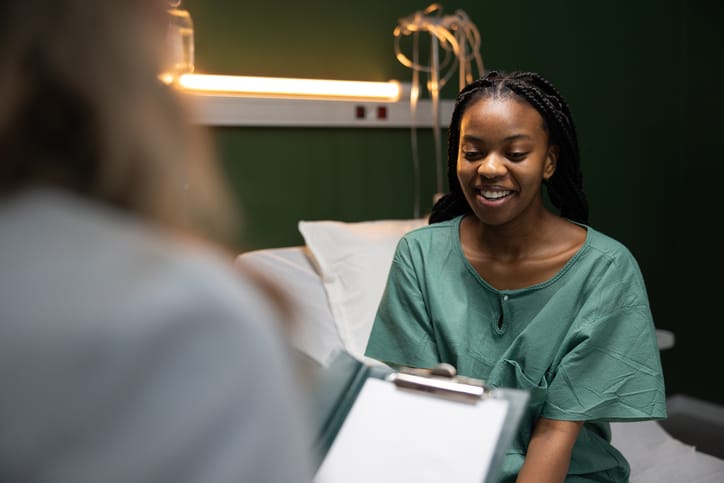 Photo shows a patient speaking to her doctor at a hospital/Getty Images