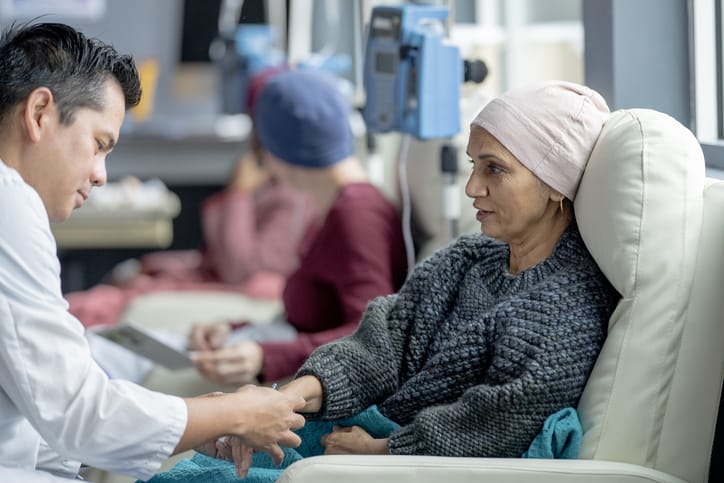 Photo shows a woman speaking to her doctor in an oncology clinic/Getty Images