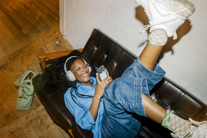 Photo shows a woman listening to music on a couch/Getty Images