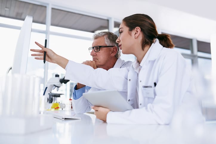 Photo shows two scientists working together on a computer in a lab/Getty Images