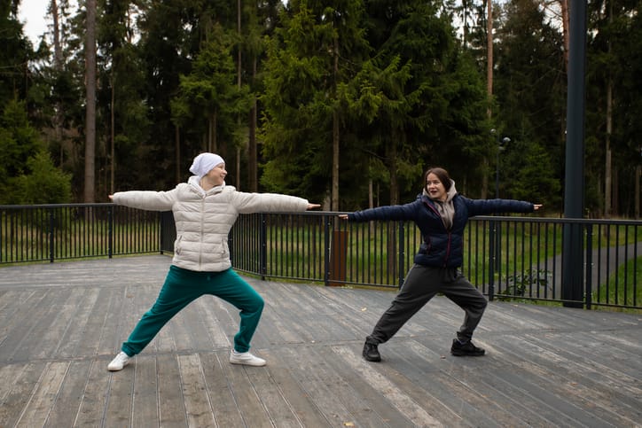 Photo shows two women doing yoga in the park/Getty Images