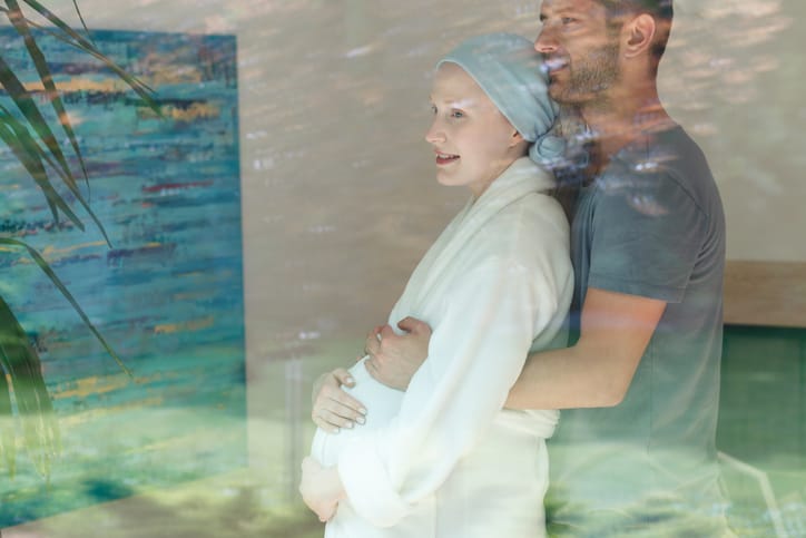 Photo shows a man hugging a pregnant woman with cancer/Getty Images