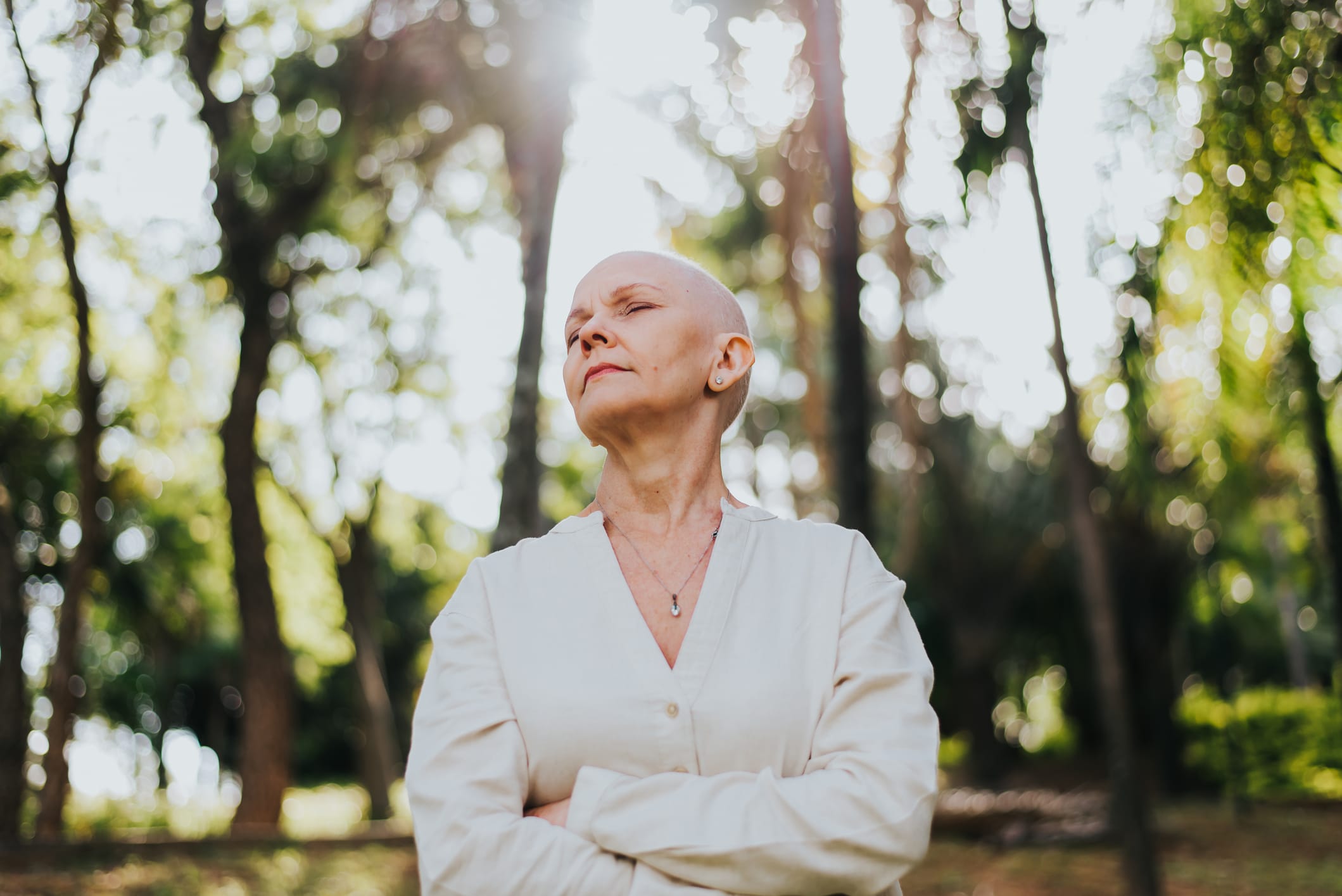 Cancer patient standing outdoors with eyes closed