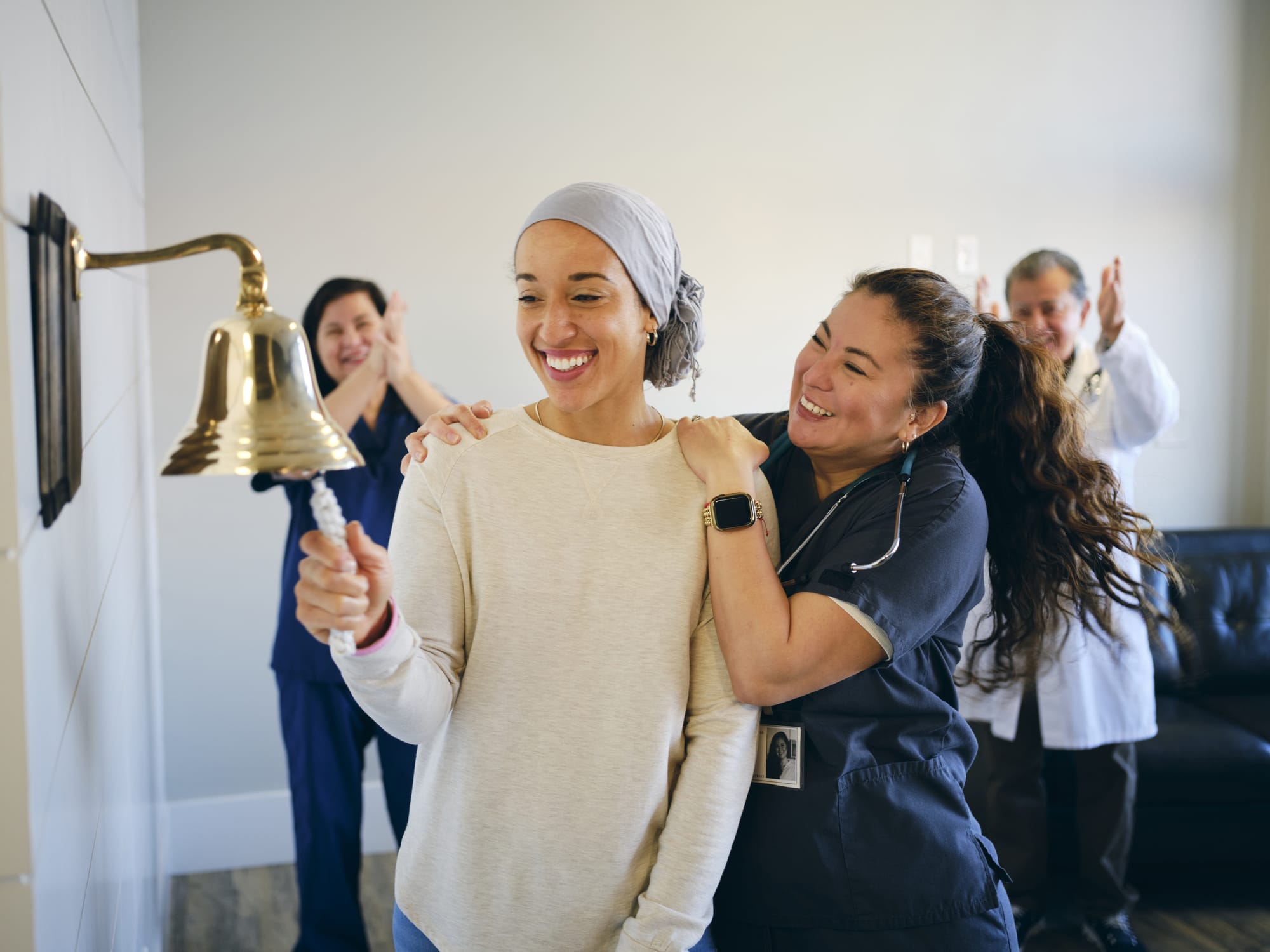 A cancer patient ringing bell, with healthcare providers clapping in background.